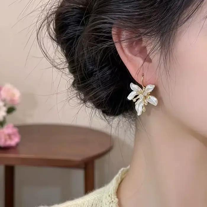 Élégantes boucles d'oreilles pendantes en émail blanc avec fleur