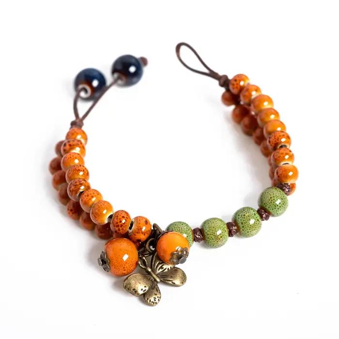 Bracelet en céramique vert-orange avec breloque papillon