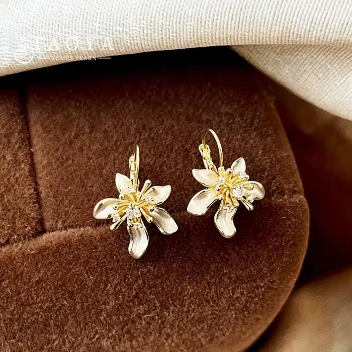 Élégantes boucles d'oreilles pendantes en émail blanc avec fleur