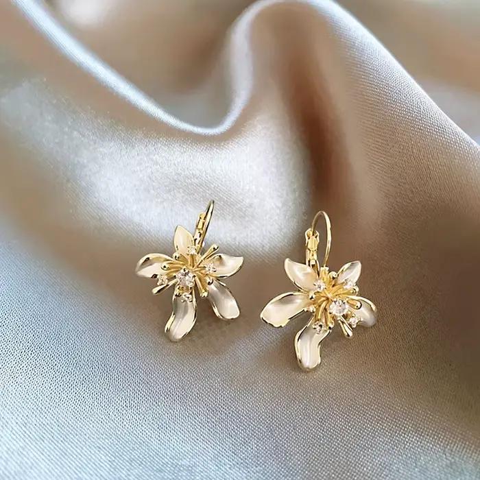 Élégantes boucles d'oreilles pendantes en émail blanc avec fleur