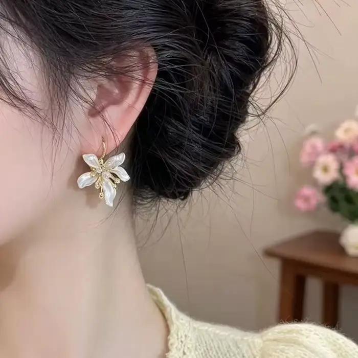 Élégantes boucles d'oreilles pendantes en émail blanc avec fleur
