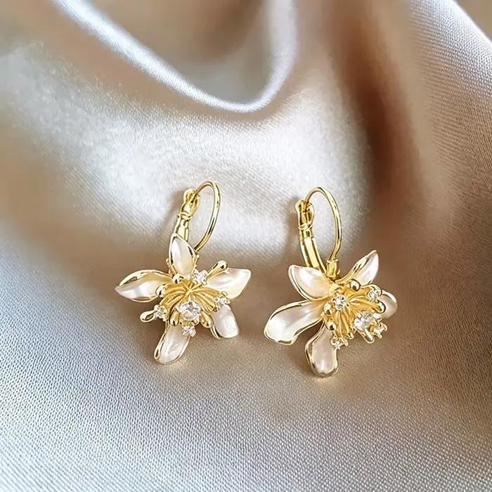 Élégantes boucles d'oreilles pendantes en émail blanc avec fleur