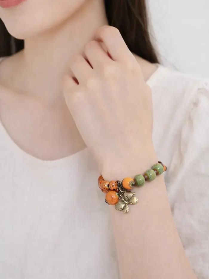 Bracelet en céramique vert-orange avec breloque papillon